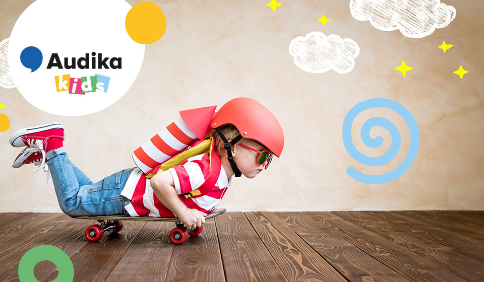 Un niño lleva un casco rojo y una mochila con diseño de cohete, acostado sobre un monopatín. Fondo de madera y dibujos decorativos. Texto: ’Audika kids.’