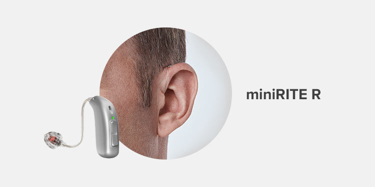 Un audífono miniRITE R de Audika está colocado detrás de la oreja de un hombre. El dispositivo es discreto y moderno, diseñado para mejorar la audición. Texto: ’miniRITE R’.
