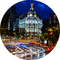 Edificio Metropolis iluminado por la noche en el centro de Madrid con tráfico en movimiento