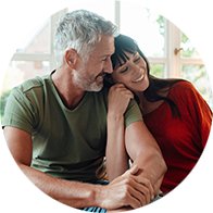 Pareja madura sentada en casa con luz natural, simbolizando comodidad y cuidado auditivo.