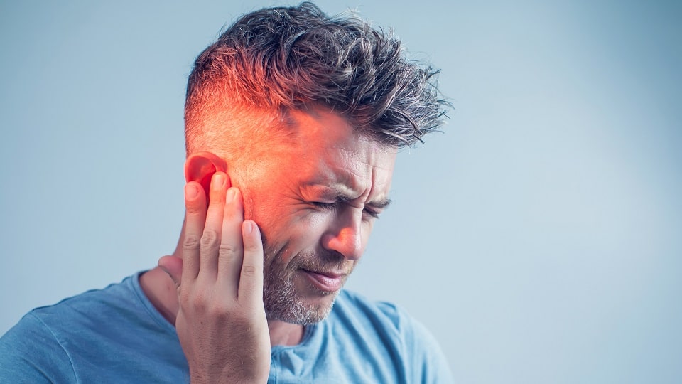 Un homme souffrant d'un acouphène qui se tient l'oreille