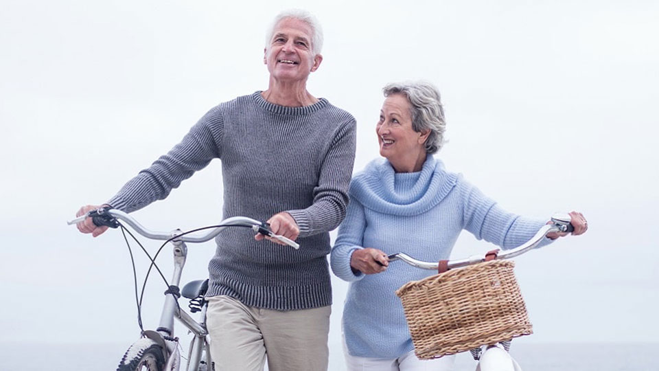 Un couple de senior faisant du vélo avec leurs aides auditives 