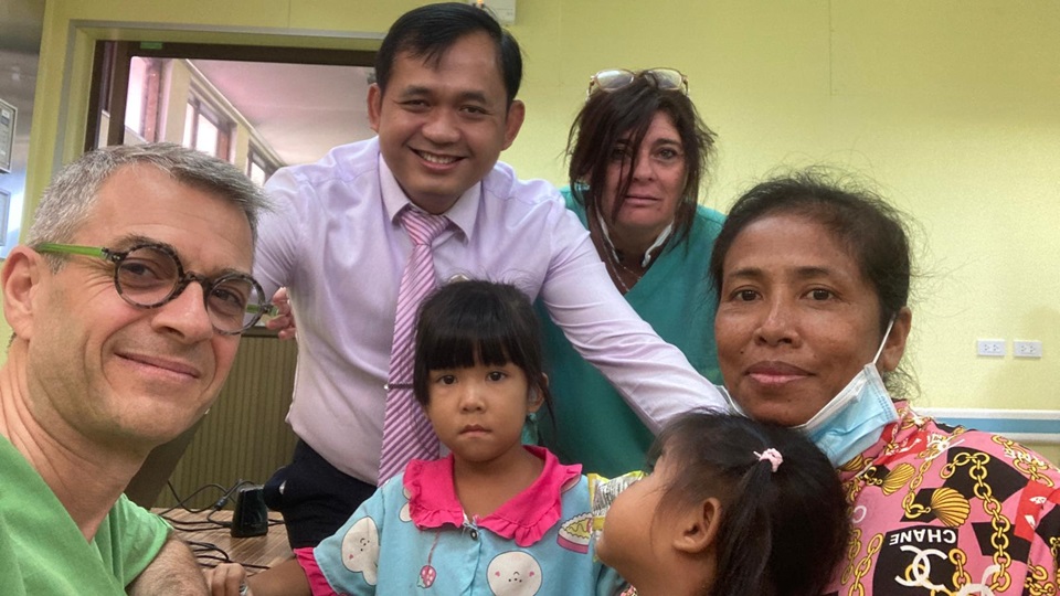 Deux audioprothésistes entourés de patients et de collègues lors d'une mission humanitaire au Cambodge en 2024.