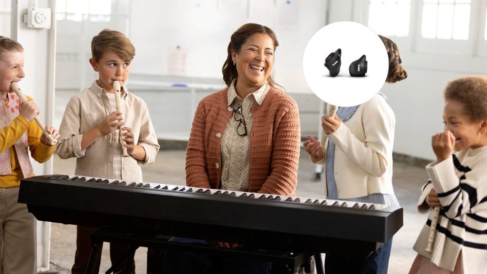 Une femme portant des embouts Snugs AirPods Pro sourit entourée d’enfants jouant de la musique sur un clavier et des flûtes.