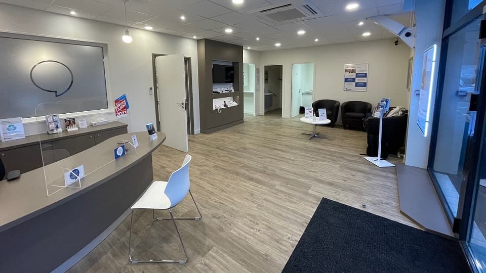 Intérieur moderne et accueillant du centre auditif Audika La Ferté Macé, comprenant un comptoir d’accueil, des sièges confortables et un éclairage chaleureux.