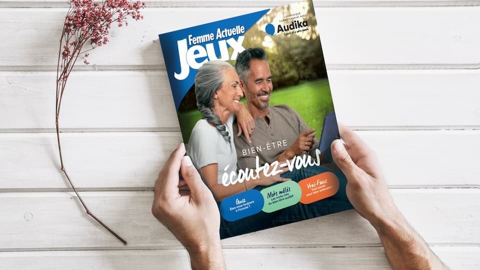 Magazine Femme Actuelle Jeux Audika axé sur le bien-être et l'audition, présenté sur une table en bois avec une branche décorative.