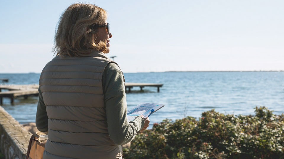 Une femme en bord de mer prend soin de ses aides auditives