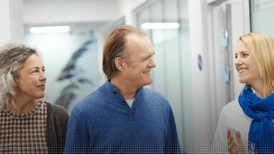 Une audioprothésiste échange avec deux patients dans un centre Audika.