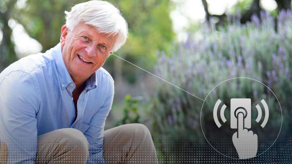 Un homme âgé utilise des aides auditives intelligentes avec contrôle tactile.