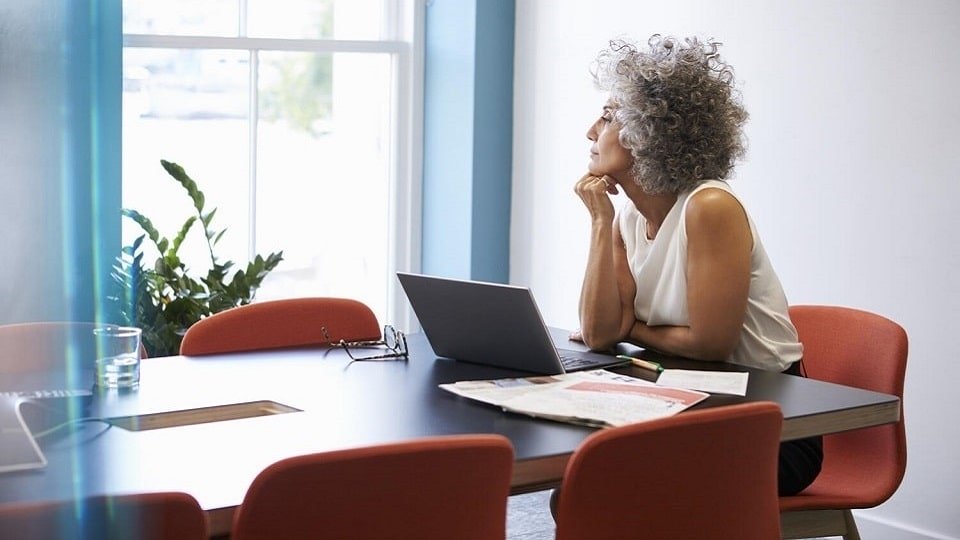 Personne pensive regardant par la fenêtre avec des appareils auditifs