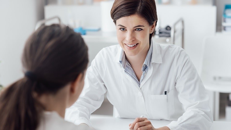 Un audioprothésiste échange avec une jeune femme lors d’un rendez-vous pour un bilan auditif.