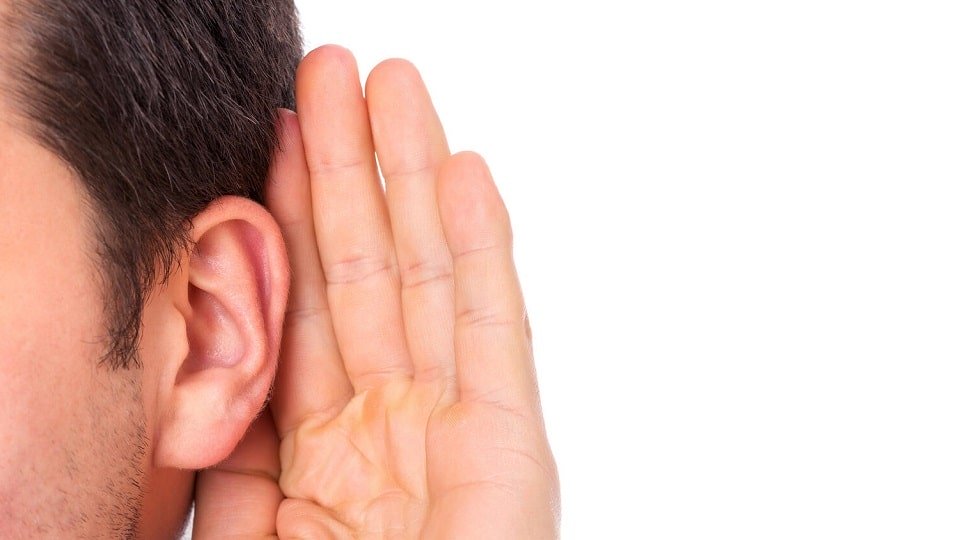 Un homme tenant sa main derrière son oreille pour améliorer son audition
