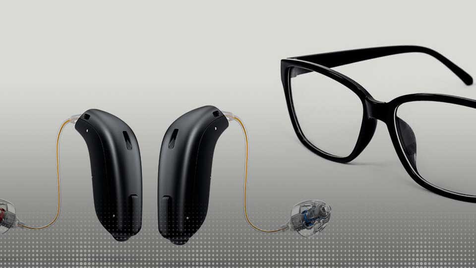 Aides auditives modernes et lunettes noires élégantes sur fond gris