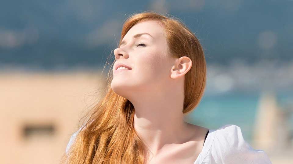 Une femme rouquine profitant du soleil tout en prenant soin de son audition