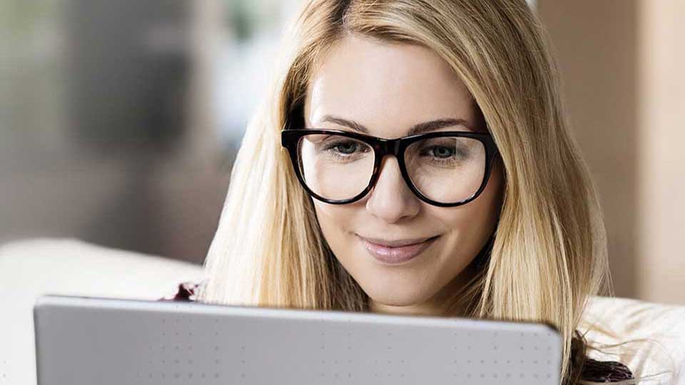 une femme utilisant des aides auditives connectées à internet tout en travaillant sur une tablette