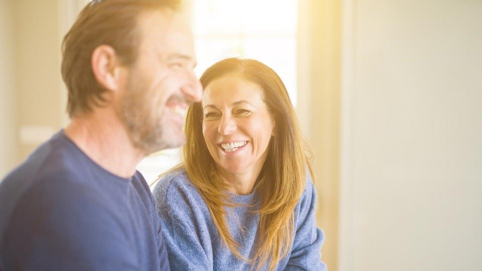 Un couple complice souriant dans une pièce lumineuse