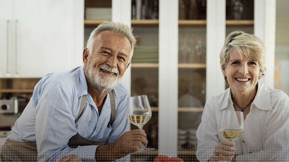Couple de seniors partageant un verre de vin blanc dans une cuisine moderne