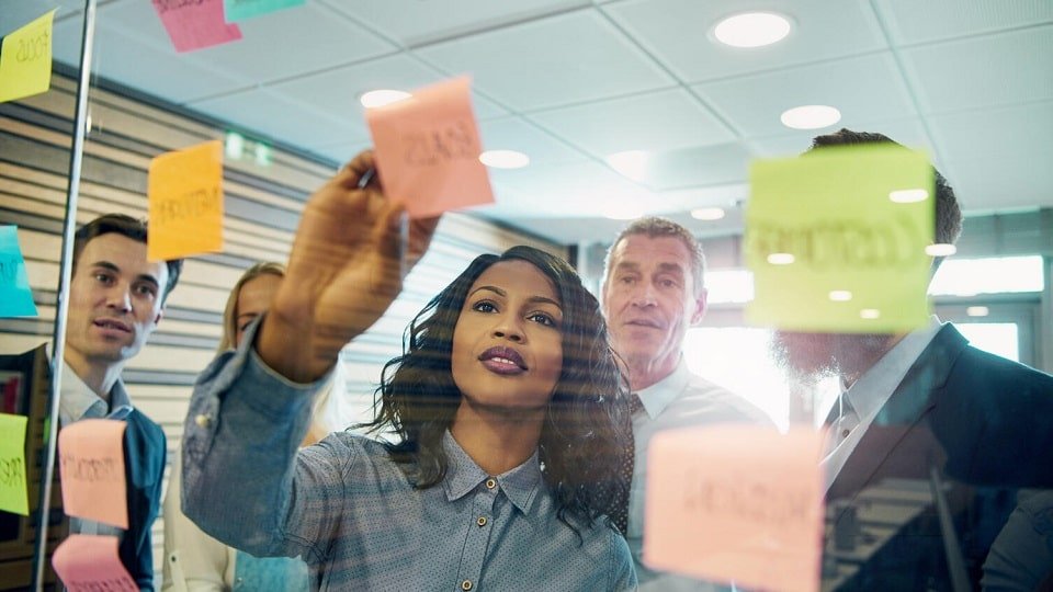 Une équipe de travail brainstorming avec des post-it, incluant des personnes portant des appareils auditifs.