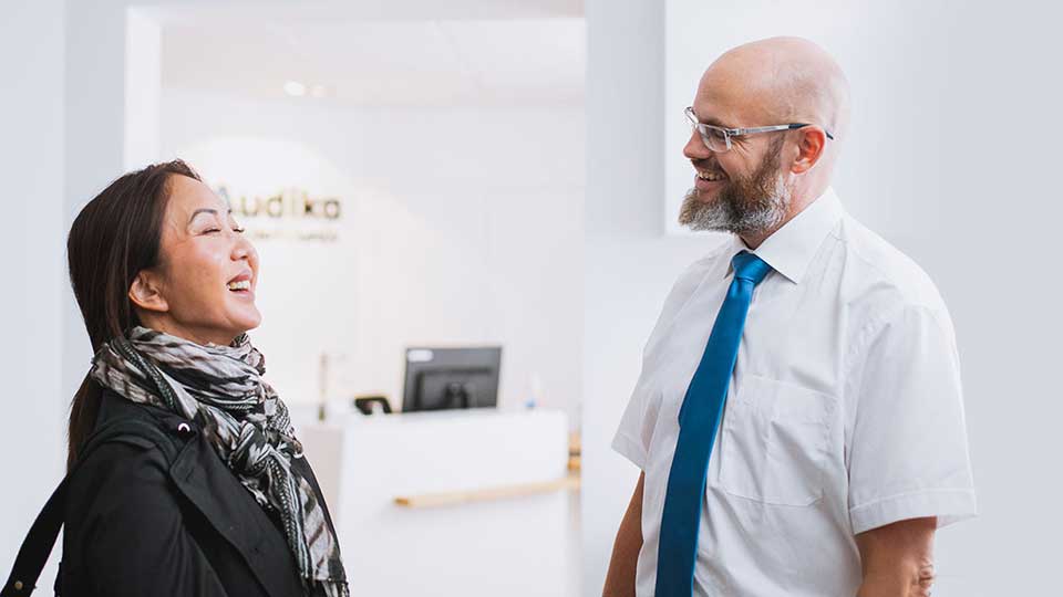 Un audioprothésiste échange avec une patiente dans un centre auditif lumineux.