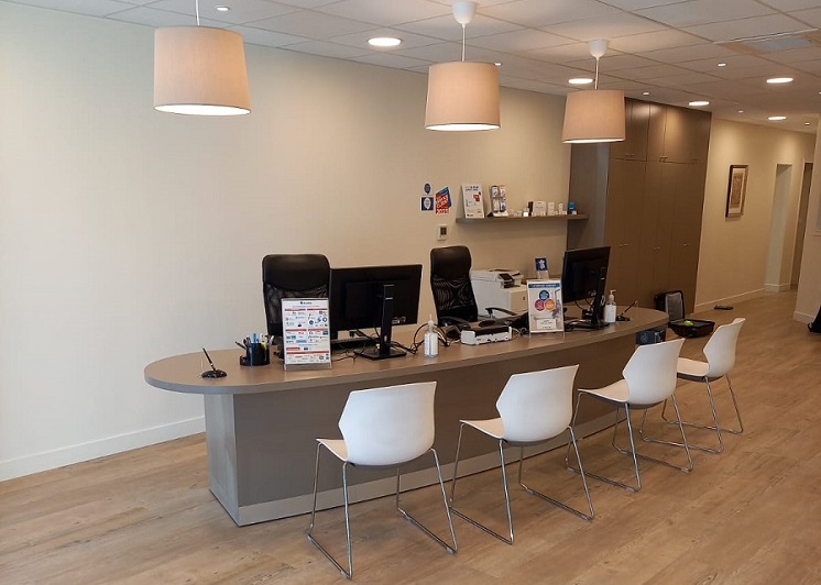 Centre auditif Audika à Draguignan avec comptoir d’accueil moderne, chaises blanches, bureaux équipés et éclairage suspendu chaleureux.