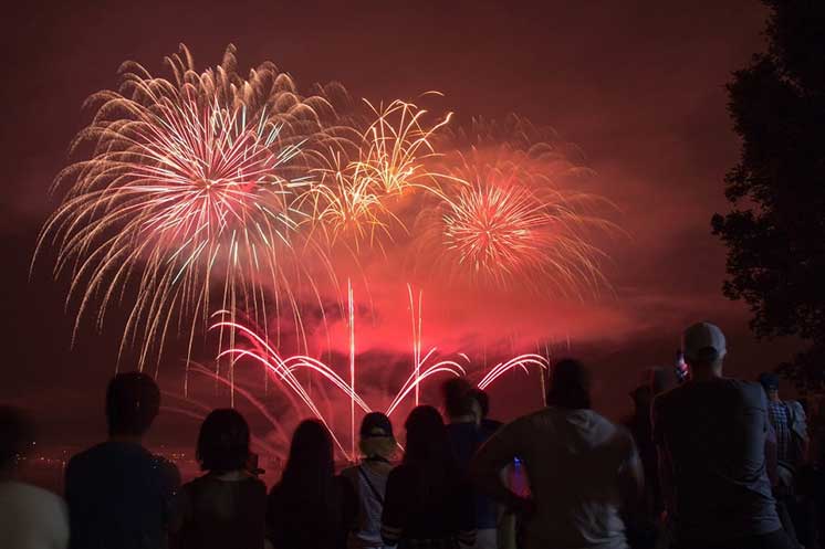Des personnes assistent à un feu d’artifice coloré dans le ciel nocturne.