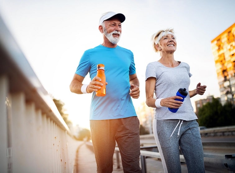 Deux personnes portant des appareils auditifs en train de courir avec des bouteilles d’eau.