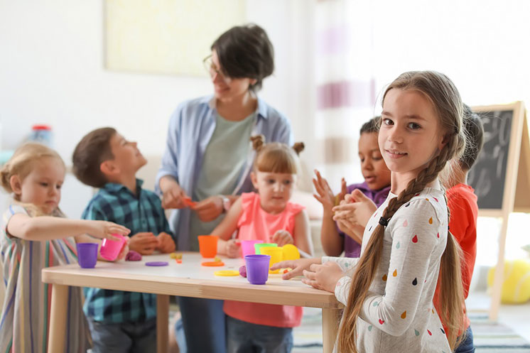 Une petite fille avec une perte auditive interagit avec d’autres enfants lors d’une activité scolaire.