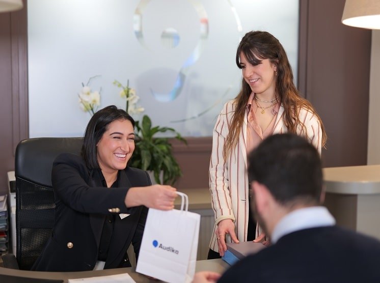 Un client au centre Audika recevant des produits et des conseils d’un audioprothésiste lors d’un rendez-vous.