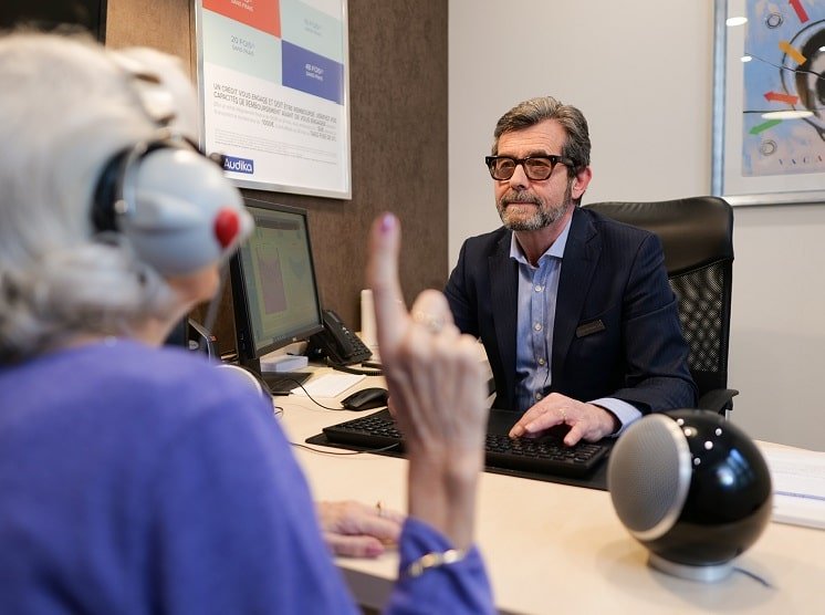 Un audioprothésiste qui fait passer le test auditif à une cliente Audika