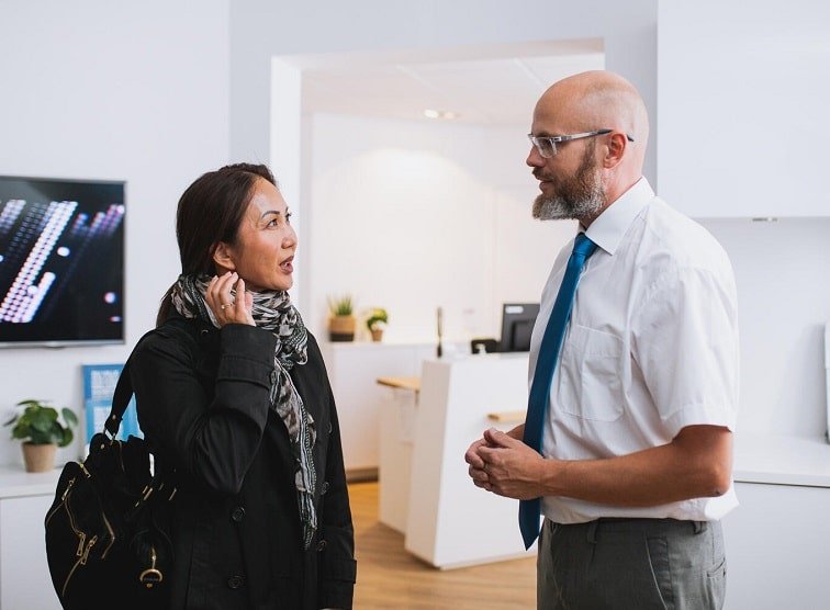 Une cliente échange avec un audioprothésiste dans un centre auditif moderne.