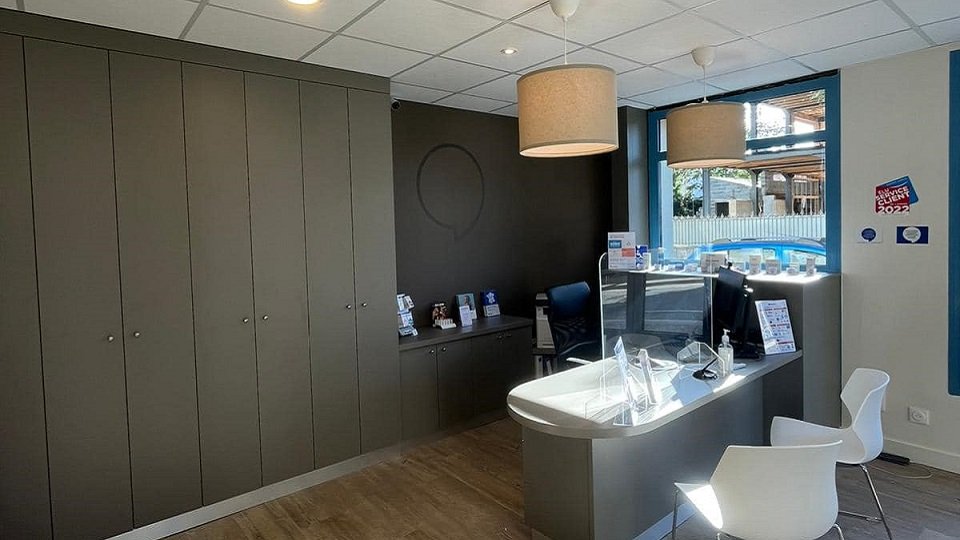 Intérieur moderne et lumineux du centre auditif Audika Chatelaillon Plage avec bureau d’accueil et présentoirs d’informations.