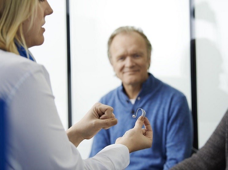 Un homme discutant des options d’appareils auditifs avec un audioprothésiste.