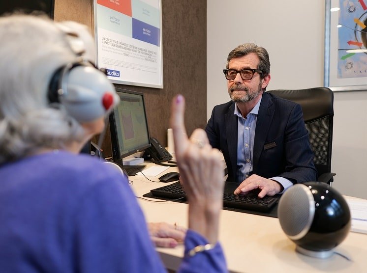 Un audioprothésiste effectuant un test auditif avec une patiente dans un centre Audika.
