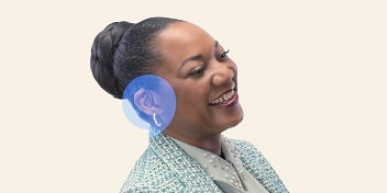 Une femme portant un appareil auditif et souriant