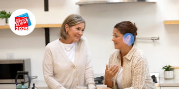 Cliente portant des appareils auditifs Audika échangeant dans une cuisine moderne.