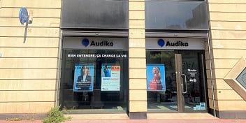 Façade du centre auditif Audika Montpellier Arceaux avec affiches publicitaires et slogan « Bien entendre, ça change la vie ».