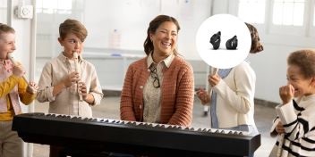 Une femme portant des Snugs AirPods Pro sourit entourée d'enfants jouant de la musique sur un clavier et des instruments.