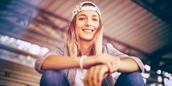 Portrait de Marie Riverau en extérieur, assise sous une structure métallique, lumière naturelle.