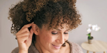 Femme examinant son oreille dans un contexte de soins auditifs