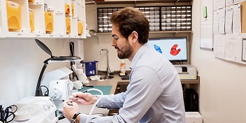 Un audioprothésiste dans le laboratoire LEA en train de manipuler des appareils auditifs