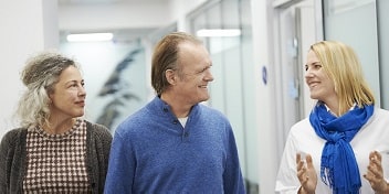 Un couple discutant avec un audioprothésiste dans un centre auditif, recevant des explications sur le processus d'appareillage auditif.