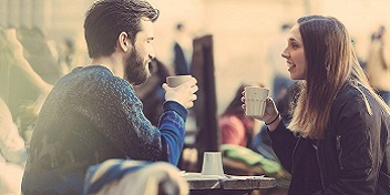 Deux personnes conversant dans un café en plein air.