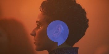 Une femme équipée d’aides auditives sous des lumières colorées dans une discothèque