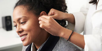 Santé auditive, femme recevant un appareil auditif placé par un spécialiste