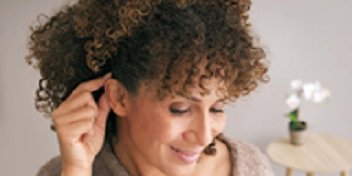 Femme examinant son oreille dans un contexte de soins auditifs