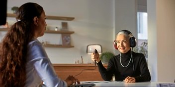 Une femme passant un test auditif guidée par une audioprothésiste dans un environnement professionnel.