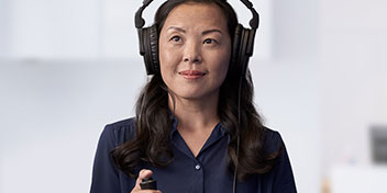 Femme portant un casque audio et tenant un appareil pour un test auditif