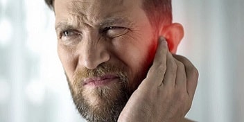 Homme touchant son oreille en raison d'acouphènes