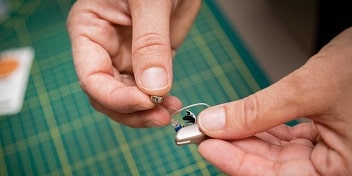 Mains ajustant un appareil auditif moderne