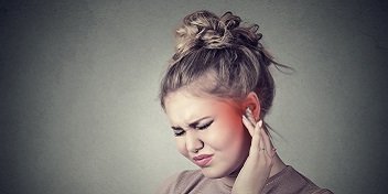 Femme ressentant une gêne auditive qui se touche l'oreille, symptomatique de l'hyperacousie.